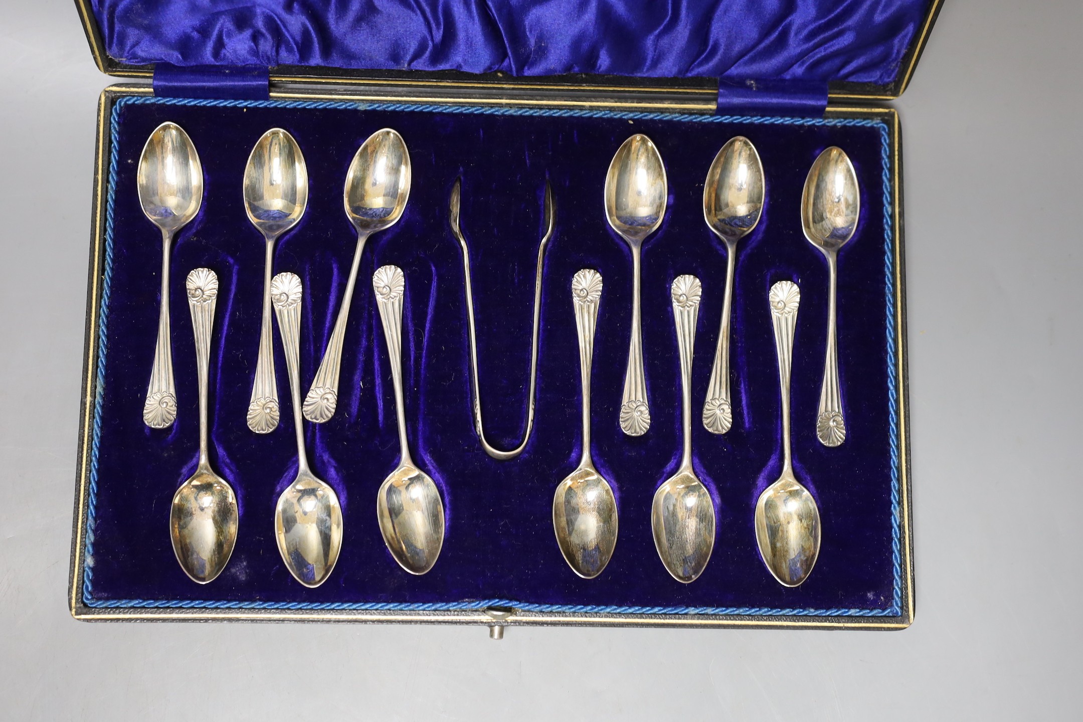 A cased set of twelve Edwardian silver teaspoons with tongs, a cased set of six tea knives and a cased set of 5 (ex 6) silver teaspoons.